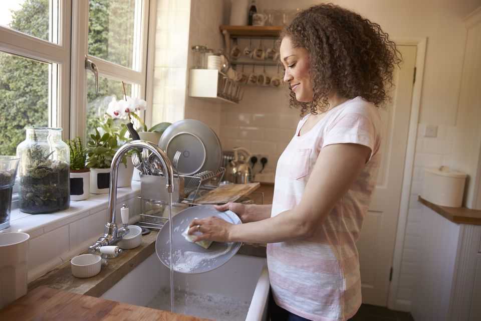 Женщина моет посуду